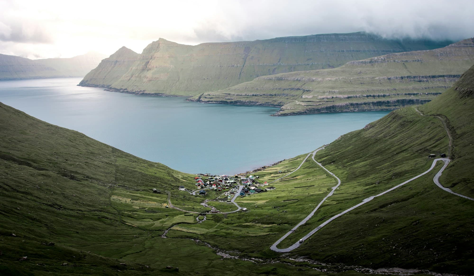 A small village between green mountains and a blue Faroese fjord